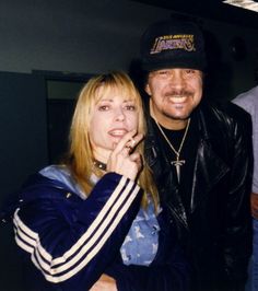 a man standing next to a woman while holding a cell phone up to her ear