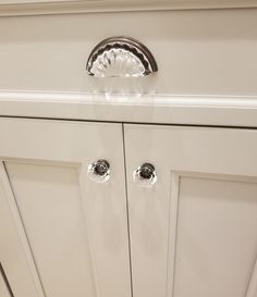 a white cabinet with chrome handles and knobs