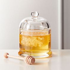 a glass jar filled with liquid next to two wooden spoons on a white table