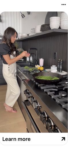 a woman standing in front of an oven cooking food on top of a stovetop