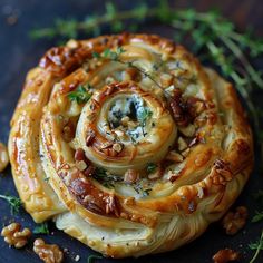 some kind of pastry with nuts and herbs around it on a black surface, ready to be eaten