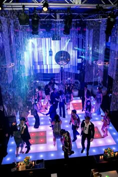 a group of people standing on top of a dance floor in front of disco lights