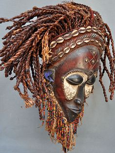 an african mask with dreadlocks on it's head is displayed against a gray background