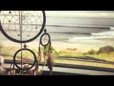 a car dashboard with a dream catcher hanging from it's side window next to the ocean