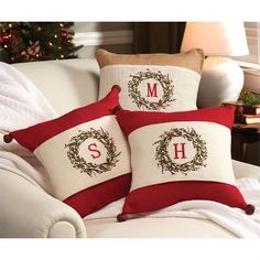 two red and white christmas pillows with the letter s on them sitting on a couch