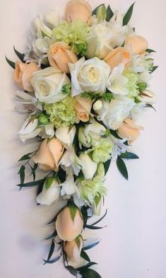 the bridal bouquet is made up of white flowers and green leaves on a wall