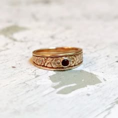 a close up of a gold ring on a white surface with a black diamond in the middle