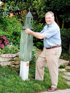 a man leaning against a green post in the grass