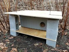 a birdhouse built into the ground in front of some dry grass