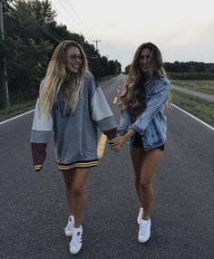 two girls walking down the road holding hands