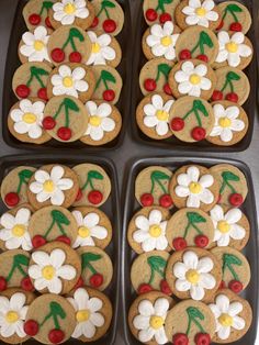 four cookies decorated with flowers and cherries on top of each other in pans