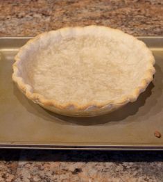 an uncooked pie crust sitting on top of a baking pan in the kitchen