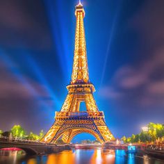 the eiffel tower lit up at night with lights reflecting in the water below