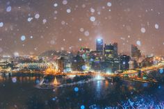 the city is lit up at night and it's snowing