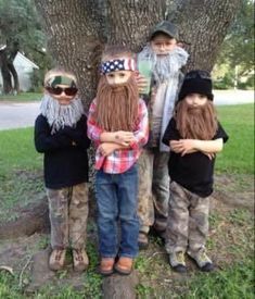 three children are standing in front of a tree with fake beards and hats on