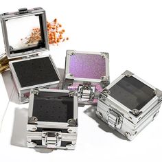 four silver cases with different designs on them and one has a mirror in the middle