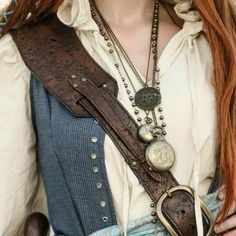 a woman with long red hair wearing a brown belt and some necklaces on her neck