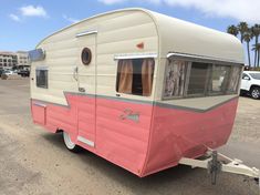 an old pink and white trailer parked in a parking lot