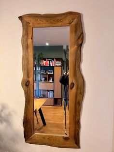 a mirror that is on the wall in front of a book shelf and bookshelf