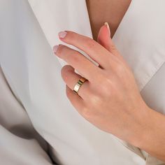 a woman's hand with a gold ring on her left wrist, wearing a white shirt