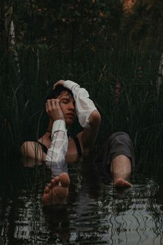 a man laying down in the water with his hands on his head while wearing suspenders