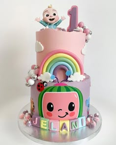 there is a pink cake decorated with animals and rainbows