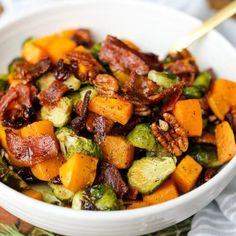 a white bowl filled with brussel sprouts, bacon and sweet potatoes