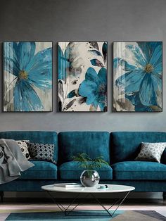 two blue flowers are hanging on the wall above a couch in a living room with grey walls