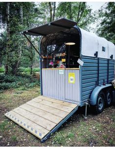 a trailer with a food cart attached to it in the middle of a wooded area