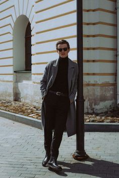 a man standing next to a pole wearing sunglasses