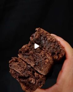 a person holding a chocolate cookie in their left hand with the white triangle on it