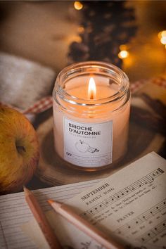 an apple sits next to a candle and sheet music