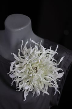 a white flower sitting on top of a mannequin