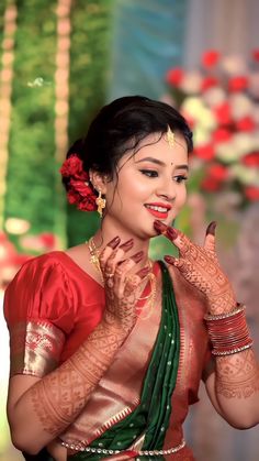 a woman in a red and green sari holding her hands up to her face