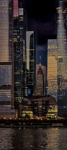 the skyline of new york city at night with skyscrapers lit up in red, white and blue