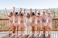 a group of bridesmaids standing on a deck with their arms in the air