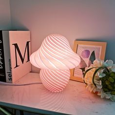 a white lamp sitting on top of a table next to a vase with flowers in it