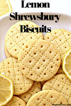 lemon shewsbury biscuits on a white plate with sliced lemons in the background