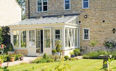 a house that has a glass roof and white trim on the side of it, surrounded by greenery