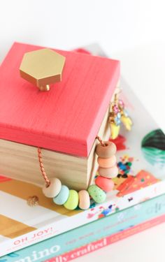 a wooden box sitting on top of a stack of books next to beads and necklaces