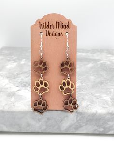 a pair of wooden earrings with dog paw prints on the front and back of them