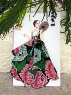 a card with a woman in a floral dress holding a fan under a tree branch