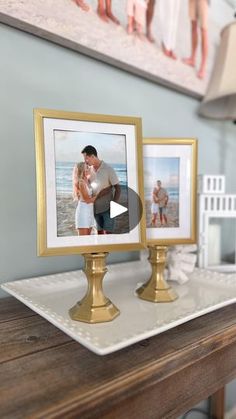 two gold framed pictures sitting on top of a wooden table