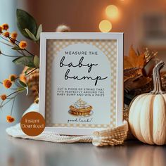 a baby bump sign sitting on top of a table next to pumpkins and flowers