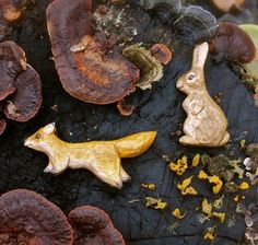 two gold colored rabbit figurines sitting on top of some mushrooms and other things