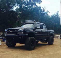 a large black truck parked on top of a dirt field