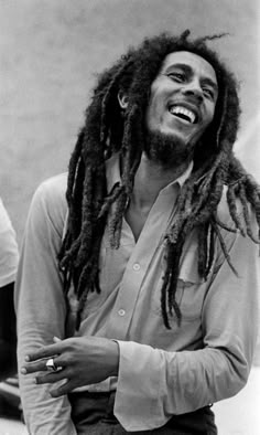 a black and white photo of a man with dreadlocks smiling at the camera