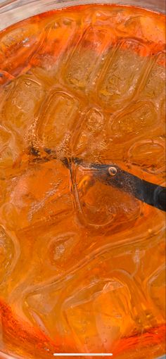 an orange liquid in a bowl with a pair of tongs sticking out of it