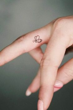 a person's hand with a small butterfly tattoo on their left thumb and finger