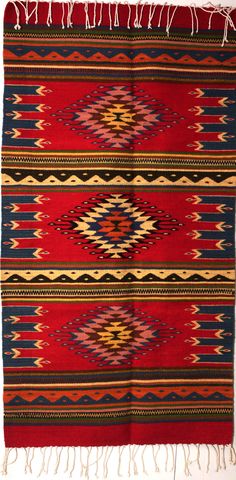 a red and blue rug with fringes on it's edges, in the shape of an arrow